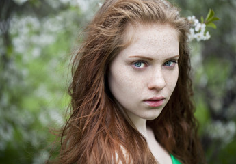 Beautiful young girl standing near blooming trees in spring gard