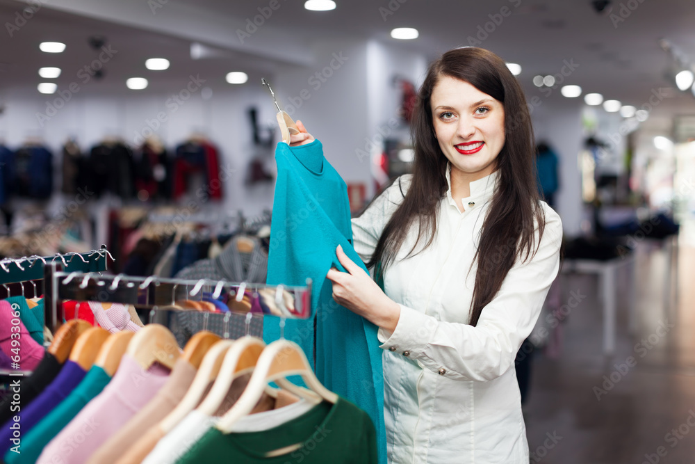 Wall mural Joyful female buyer choosing sweater