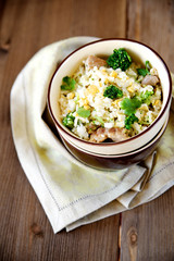 Rice dish with broccoli, meat and eggs on old wooden table