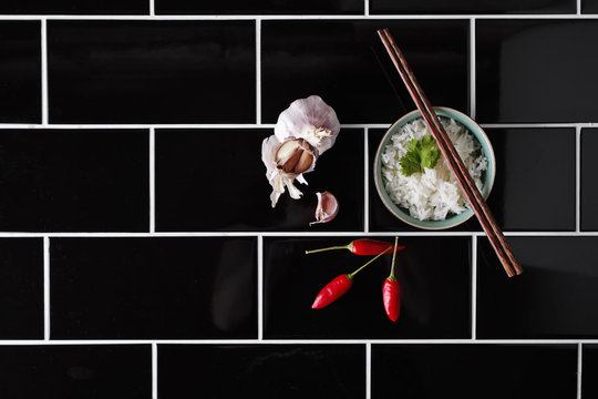 Asian rice dish and ingredietns on black railway tiles
