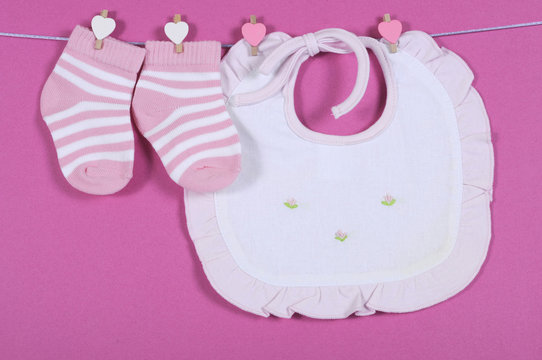 Baby girl  socks and bib hanging from pegs on a line