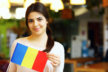 Happy female student holding flag of Romania