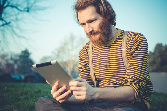young bearded stylish handsome hipster man using tablet