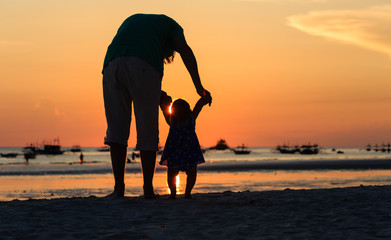 Silhouette of father and daughter on the beach