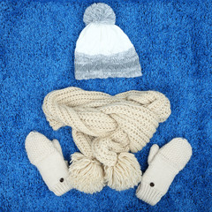 Winter cap, scarf and mittens, on color background
