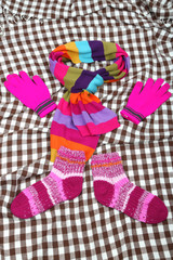 Winter scarf, gloves and socks, on color background