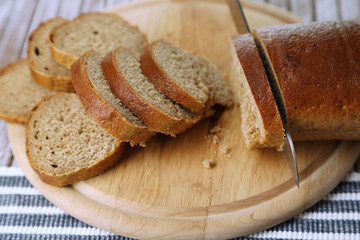 Female hands cutting bread on wooden board, close-up