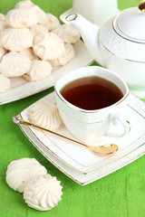 Cup of tea with meringues on table close-up