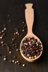 Spice pepper in spoon on wooden background
