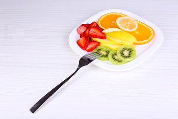 Fototapeta na wymiar Various sliced fruits on plate on table close-up
