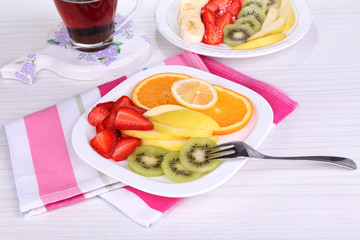 Various sliced fruits on plates on table close-up