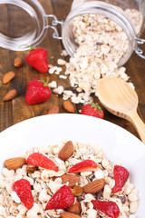 Healthy cereal with strawberry and nuts on wooden table