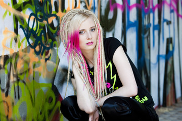 portrait of young woman sitting at graffitti wall