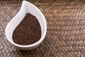 Dried tea leaves in a white ceramic container 
