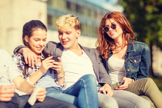 group of students or teenagers with smartphones