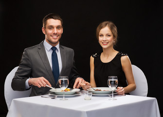 smiling couple eating main course at restaurant