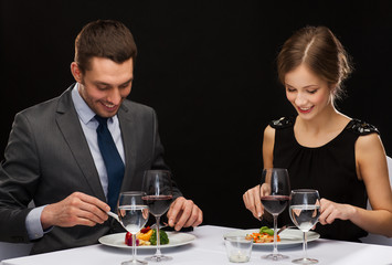 smiling couple eating main course at restaurant