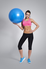 Happy fit woman holding blue fitness ball