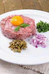 Delicious steak tartare with yolk on plate on table close-up