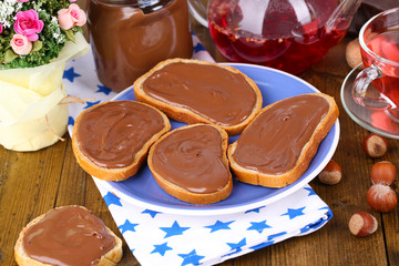 Bread with sweet chocolate hazelnut spread on plate on table