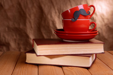 Cup with mustache on table on brown background