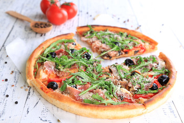 Pizza with arugula on color wooden background