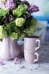 Composition with tea mugs and beautiful spring flowers in vase,