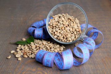 Raw green coffee beans in glass cup and measuring tape,