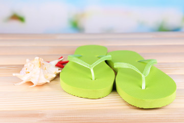 Bright flip-flops on wooden table, on nature background