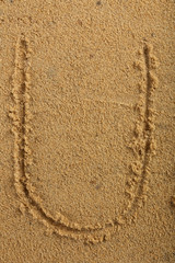 Fototapeta na wymiar Alphabet letter written on wet beach sand