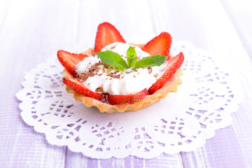 Tasty tartlet with strawberries on table close-up