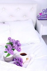 Wooden tray with light breakfast on bed