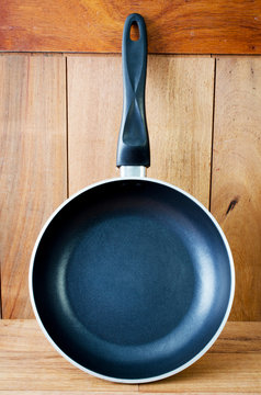 iron frying pan on wooden wall background .