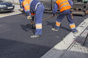 Workers on Asphalting paver machine during Road street repairing works 