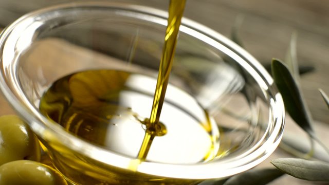 Olive oil dripping on bowl close up