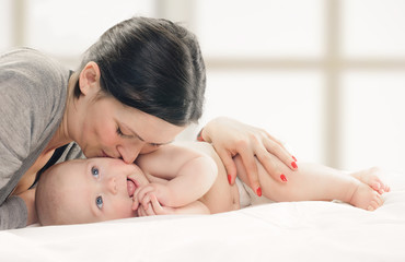 Obraz na płótnie Canvas Mother kissing happy baby on cheek