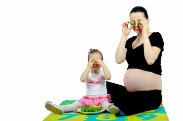 Isolated first child playing to her pregnant mother with fruits