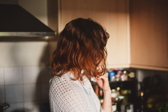 Young woman standing in her kitchen and thinking