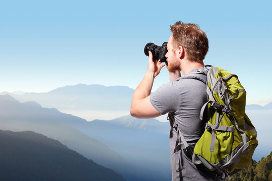 Young man taking photo on top of mountain