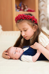 Older sister hugging baby lying on the bed