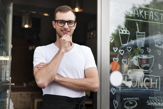 Portrait of smiling male waiter outside the cafe