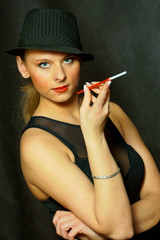 Piekna kobieta w kapeluszu z papierosem.