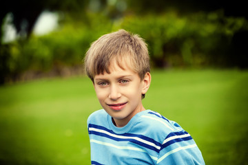 Beautiful happy child playing on grass in a sunny park smiling