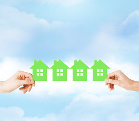 man and woman hands with many green paper houses