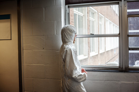 Scientist in boiler suit by window