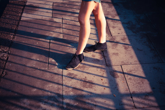 The legs of a young woman standing in the street