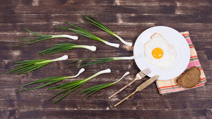 Egg , chives,  plate, knife and fork look like sperm competition