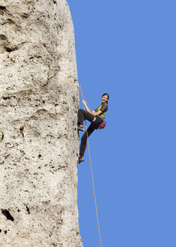 Happy woman climbing rock, active holidays.