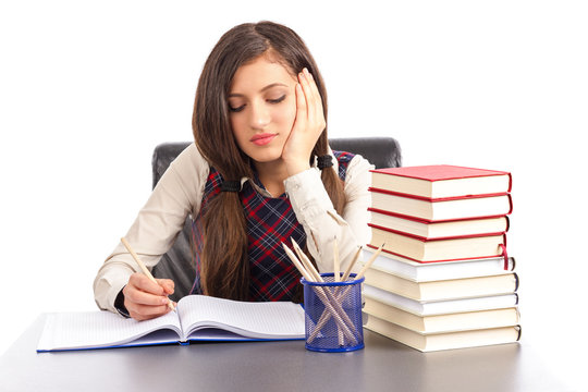 Portrait of  bored schoolgirl doing his homework at  desk