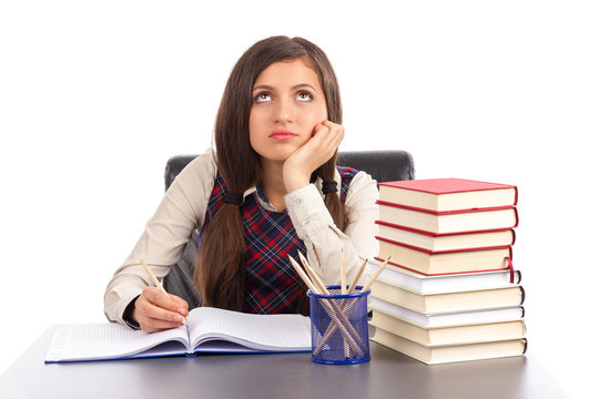 Portrait of bored schoolgirl doing his homework at desk